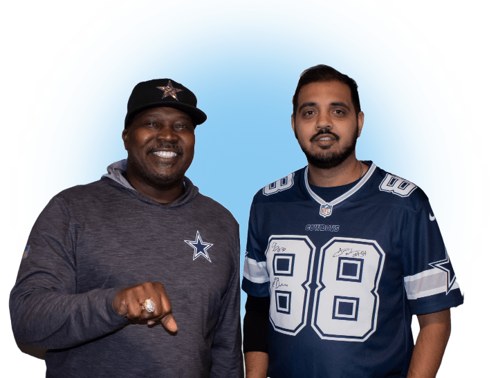 Two men are standing side by side against a blue background. The man on the left, wearing a cap and hoodie, holds out a ring like it's the answer to low-cost colonoscopy concerns. The man on the right sports a jersey with the number 88, both wear determined expressions.